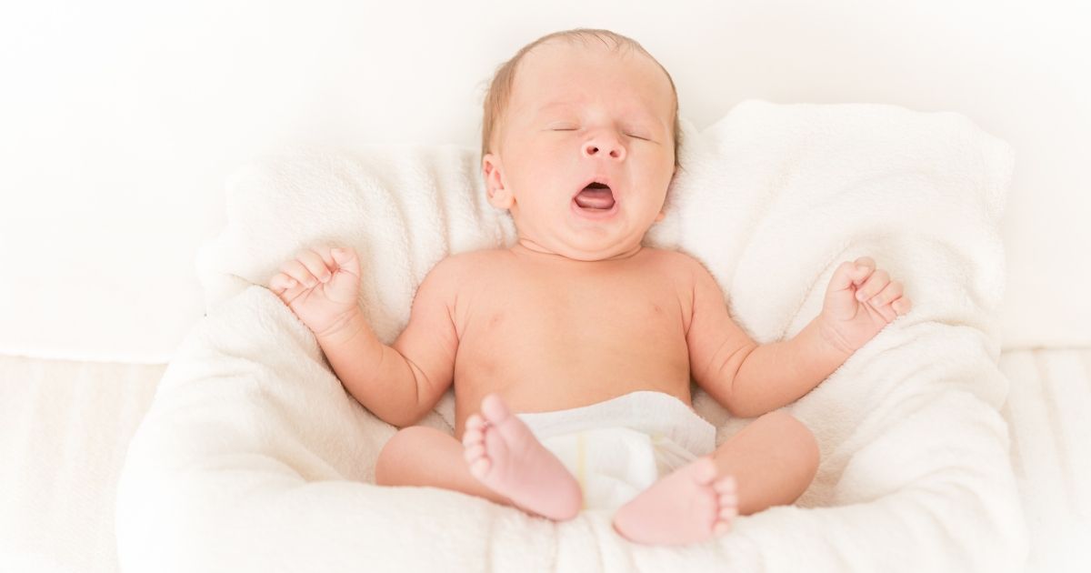Porträt eines süßen Babys, das im Bett liegt und gähnt