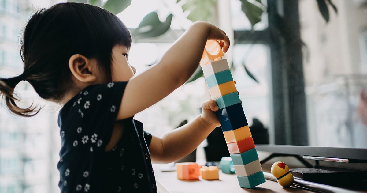 Loominguline väikelapse tüdruk, kes mängib kodus värviliste ehitusplokkidega